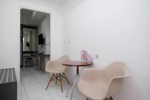 梭罗RedDoorz Apartment near Exit Toll Colomadu的一间带桌子和两把白色椅子的用餐室