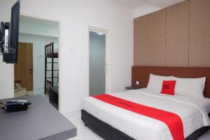 梭罗RedDoorz Apartment near Exit Toll Colomadu的一间卧室配有一张带红色枕头的大床