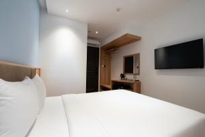 胡志明市Haven Hut Riverside Hotel的卧室配有白色的床和平面电视。