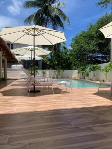 蓝海湾Le Clos des Bains Mauritius的游泳池旁带桌子和遮阳伞的天井