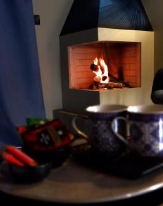 比亚恩卡维拉PODERE DELL'ETNA SEGRETA - Essential Nature Hotel的壁炉,桌子上放着两个茶杯
