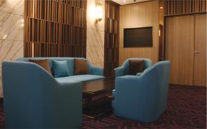 新加坡Aqueen Prestige Hotel Lavender的一间设有两把蓝色椅子和电视的等候室