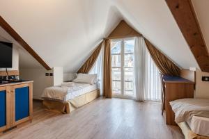 迪马罗Hotel garni Meledrio的阁楼卧室设有两张床和窗户。