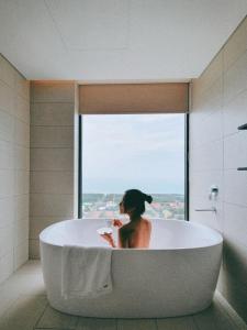 绥和市Apec Mandala Condotel Sea View Comhomes Phú Yên的坐在浴室浴缸里的女人
