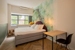 乌得勒支Badhuis Hotel的一间卧室配有一张床、一张桌子和一个窗户。