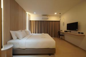 美索Alto Hotel M的一间卧室配有一张床、一张书桌和一台电视