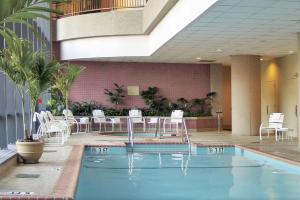 贝塞斯达Embassy Suites by Hilton Bethesda Washington DC的酒店内带白色椅子和桌子的游泳池
