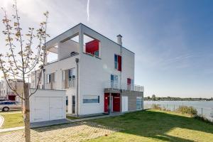 卡珀尔恩Ostseewind: Wasserblick, finnische Sauna, Whirlwanne, Kamin, 2 Parkplaetze的白色的房子,有红色的窗户和水体