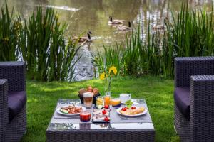 克雷费尔德Hotel Dusseldorf Krefeld Affiliated by Meliá的一张带食物和饮料的野餐桌和一个池塘