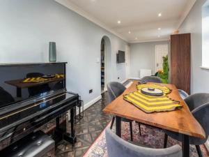 里克曼斯沃斯Pass the Keys Stylish Modern 3 bed house with Parking的一间带桌子和钢琴的用餐室