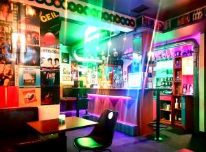 费尔德基希Hotel am Bahnhof的酒吧配有桌椅和 ⁇ 虹灯