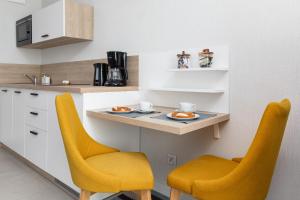 米兹多洛杰Sunny Apartments in Bel Mare Resort by Renters的厨房配有2把黄色椅子和台面