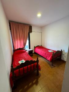 恩鲍斯4 Ases Hotel的一间卧室设有两张床,窗户配有红色床单。