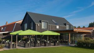 NoordeloosB&B Restaurant Maria Johanna Hoeve的一座配有桌子和绿色遮阳伞的建筑