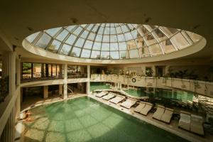 克卢日-纳波卡阳光花园高尔夫及Spa度假酒店的一个带椅子的室内游泳池和一个玻璃圆顶