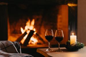 古多里Alpina Hotel的两杯葡萄酒和一张壁炉桌上的蜡烛
