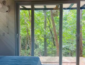 El PlantelAgora at Playa Maderas - Surf House, Cabanas and Casitas的卧室设有滑动玻璃门,享有森林美景