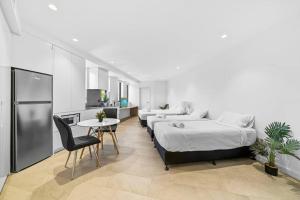 悉尼Lovely Studio apartments in Strathfield CBD的一间带两张床和一张桌子的卧室以及一间厨房