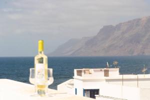 法马拉Casa Bianca Caleta De Famara的坐在靠近大海的一座建筑的顶部,一瓶葡萄酒