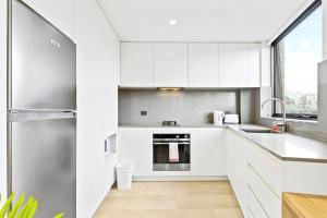 悉尼Lovely Studio apartments in Strathfield CBD的厨房配有白色橱柜和不锈钢冰箱