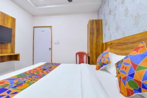 艾哈迈达巴德FabHotel Star的卧室配有白色床和色彩缤纷的被子