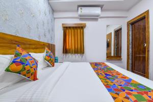 艾哈迈达巴德FabHotel Star的卧室配有一张带彩色枕头的大型白色床。