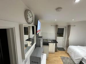 布罗姆利1st Studio Flat With full Private Toilet And Shower With its Own Kitchenette in Keedonwood Road Bromley A Fully Equipped Independent Studio Flat的卧室配有一张床,墙上挂着一个钟