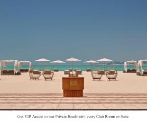 阿布扎比Emirates Palace Mandarin Oriental, Abu Dhabi的海滩上的一个讲台,上面摆放着椅子和遮阳伞