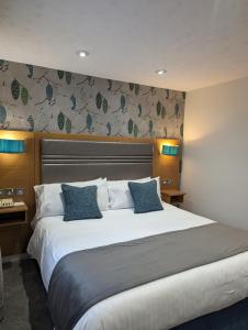 哈德斯菲尔德石楠府酒店的卧室配有带蓝色枕头的大型白色床
