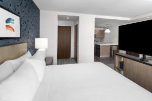 兰辛Hyatt House Lansing-University Area的卧室配有白色的床和平面电视。