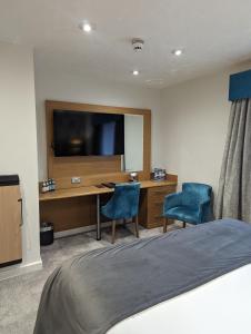 哈德斯菲尔德石楠府酒店的一间卧室配有一张桌子、一台电视和两把椅子