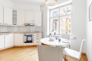 赫尔辛基Cozy, spacious and calm city home - top location的厨房配有白色橱柜和白色的桌椅