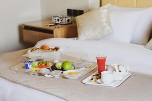 开罗Arabella Premium Residence - New Cairo的床上装有食物和饮料的托盘