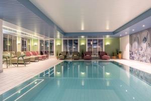 达沃斯Central Sporthotel Davos的酒店大堂的游泳池,配有桌椅