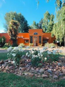 图努扬Finca La Saucina Casa de Campo的一座橙色的房子,前面有一个岩石花园