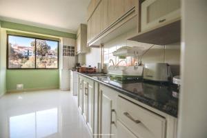 苏克雷Cómodo y amplio departamento con vistas inmejorables的一间厨房,配有白色的橱柜和大窗户