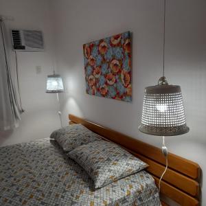 塞古罗港Apartamento inteiro n.24的一间卧室配有一张带灯具和绘画的床