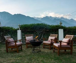 马拉里The Wooden Chalet, Manali by DBP的四把椅子和一个山地火坑