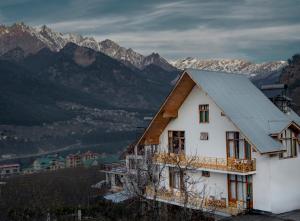 马拉里The Wooden Chalet, Manali by DBP的白色的房子,拥有灰色的屋顶和山脉