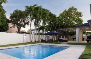迈阿密Miami Luxury Villa Heated Pool & Pool Table 5BD 4BR的一个带遮阳伞和棕榈树的游泳池
