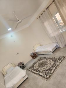 MisfāhSunset view hill jabal shams的客厅配有两张床和地毯。