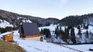 贝拉内Owl House Jelovica的一座小建筑,在白雪 ⁇ 的山坡上,种着树木