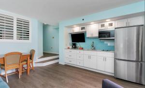 默特尔比奇4800 S Ocean Blvd, 0915 - Ocean Front Sleeps 6的厨房配有白色橱柜、桌子和冰箱。