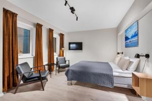 特罗姆瑟Bispegata 5 - Studio Apartment hotel的一间卧室配有一张床、两把椅子和一台电视