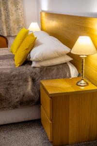 利兹Beechwood Accommodation in North Leeds的一张带木制床头板的床和一张带台灯的桌子