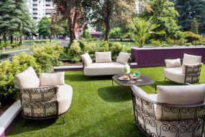 米兰达文西酒店的庭院配有白色的椅子、桌子和草地