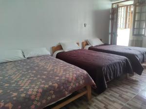奥克萨潘帕Hospedaje Pinky Lodge的一间房间,有三张床