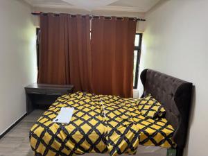 卢萨卡Steady State Apartment 1的一间卧室配有一张黄色和黑色棉被的床