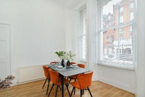 伦敦London Choice Apartments - Gloucester Road - Kensington的一间带桌子和橙色椅子的用餐室