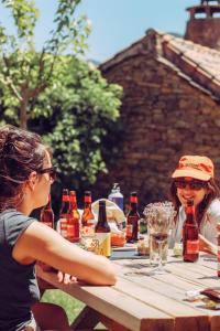 Casa Rural Ger的两个女人坐在野餐桌上,喝着啤酒